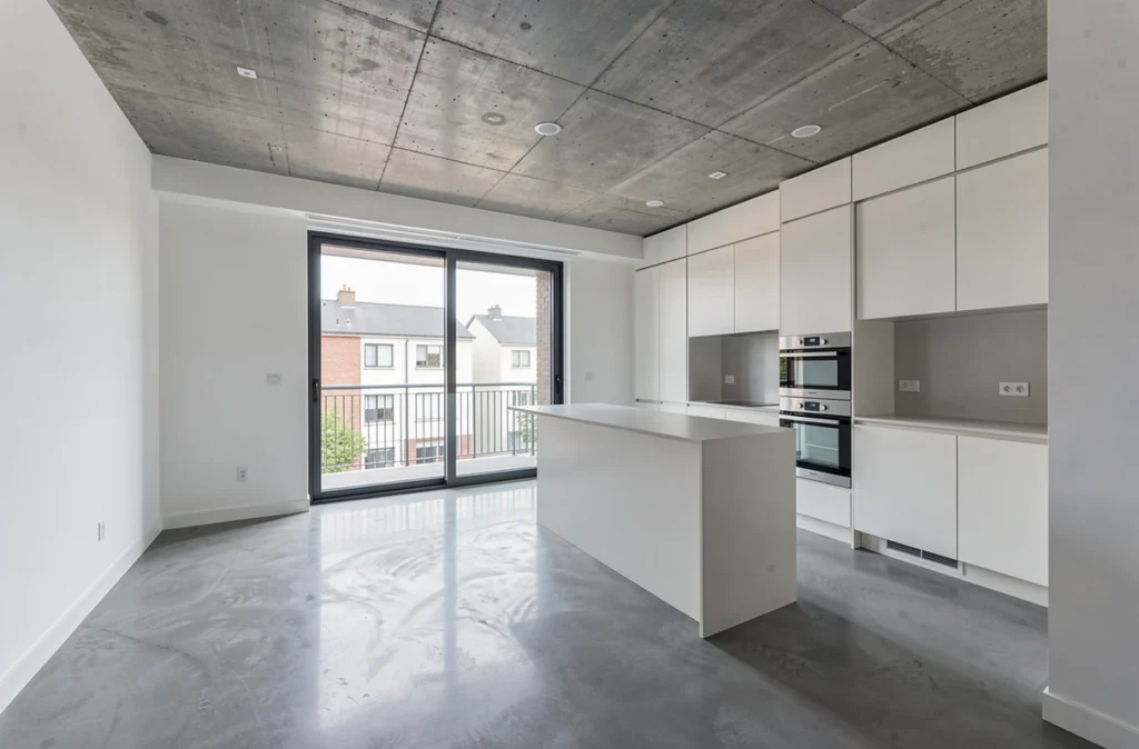 Intérieur d'appartement neuf vide avec sol en micro-ciment et plafond en béton apparent tendance architecture contemporaine