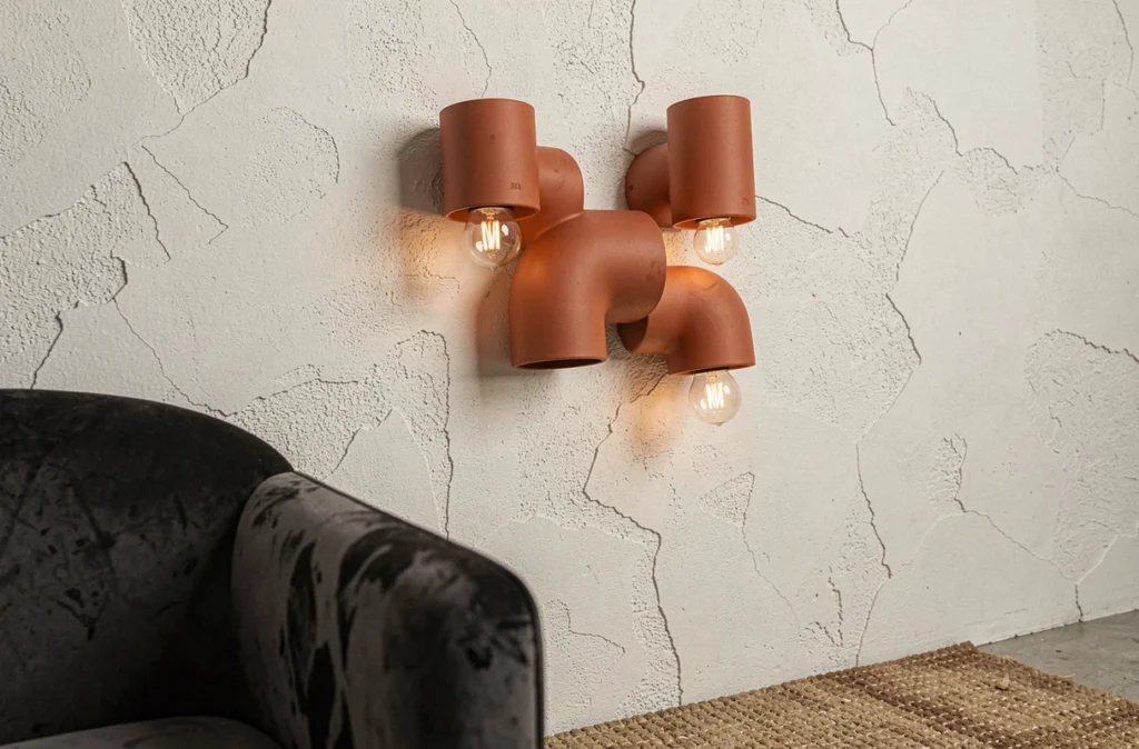 Trio d'appliques murales modulaires en céramique terracotta disposées en grappe asymétrique sur un mur en plâtre blanc dans un séjour urbain